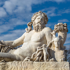 A statue of the Colossus Nile in the Jardin des Tuileries in Paris against a bright blue sky with white clouds