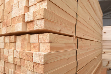 Many folded wooden planks in a warehouse with a forest