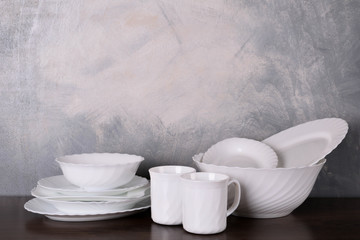  White dishware stacked on a wooden table against grey background on wooden table