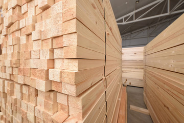 Many folded wooden planks in a warehouse with a forest