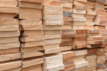 Texture of folded wooden planks in a warehouse with a forest. View from the end