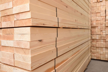 Many folded wooden planks in a warehouse with a forest