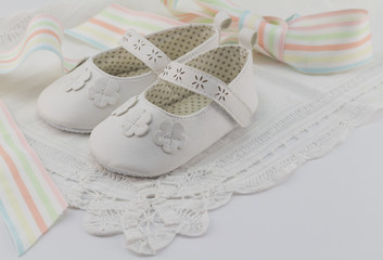 Baby booties background with white lace and pastel colour ribbon, suitable for babtism, christening, birthday or baby shower invitation with space for text