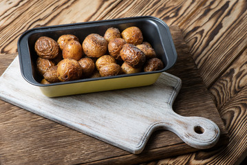Baked homemade potatoes are in a metallic form on a wooden background