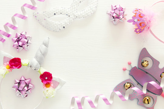girl's party concept. unicorn head decoration, pink wand, mask and toy over white wooden background.