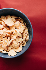 delicious crispy cornflakes in bowl on red background,  healthy breakfast