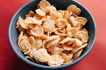 delicious crispy cornflakes in bowl on red background,  healthy breakfast