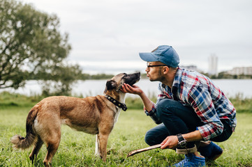 Adult stylish man playing with loving pet. Family outdoor. Animal lover. Happy dog enjoying freedom. Terrier breeding puppy have fun with owner. Furry crazy canine training at nature. Friends together