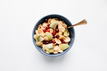 Delicious crispy cornflakes with kiwi pieces and cranberries in bowl, closeup, healthy breakfast