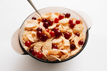 delicious crispy cornflakes with cranberries in bowl on white background, closeup, healthy breakfast 