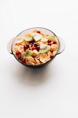 delicious crispy cornflakes with kiwi pieces and cranberries in bowl on white background, closeup, healthy breakfast 