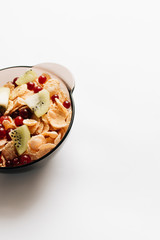 delicious crispy cornflakes with kiwi pieces and cranberries in bowl on white background, closeup, healthy breakfast 