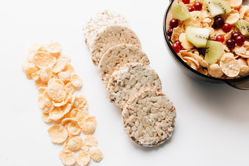 crisp bread and delicious crispy cornflakes with kiwi and cranberries in bowl over white background,  healthy breakfast