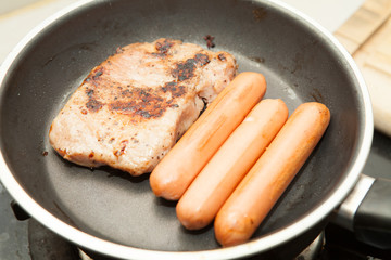 Pork steak with pepper and sausage fried in pan