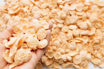 female hand holding pile of delicious crispy cornflakes, food background,  healthy breakfast