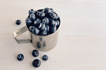Fresh organic blueberries in metal mug on wooden table. Sweet blueberry fruit for juice or smoothies, health food for  raw diet. Berries background.Copy space.