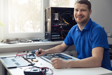 smiling young electronics technician at work - obrazy, fototapety, plakaty