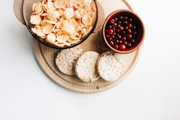 delicious crispy cornflakes in bowl with cranberries and almonds  on white background,  healthy breakfast