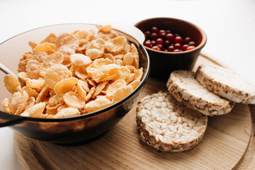 delicious crispy cornflakes in bowl with cranberries and almonds  on white background,  healthy...