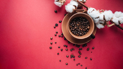 cup of black coffee, coffee beans and cotton flowers on dark background 