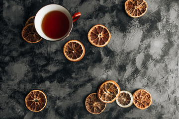 slices of dry oranges  and cup of tea on dark stone table