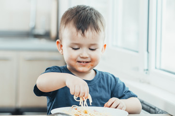 The child in the kitchen at the table eating macaroni and interesting view from the top