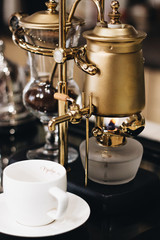 Fototapeta na wymiar Cup of delicious coffee and retro style coffee machine, closeup