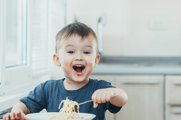 The child in the kitchen at the table eating macaroni and interesting view from the top