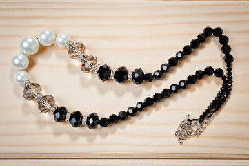 Beads of black and white pearls on a wooden background