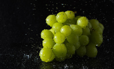 Trauben mit Wassertropfen vor schwarzem Hintergrund
