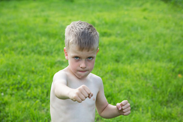little boy boxing on the lawn on a summer day