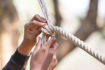Man's hands is solving the knot on the tree. Tied to the base to climb the rope. Media visualization of the problem and learn how to fix it. Soft focus and copy space.