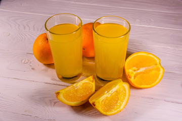 Oranges and glasses with orange juice on a wooden table