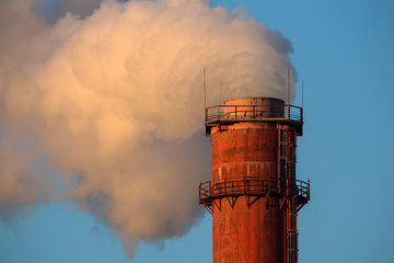 smoking chimneys of a power plant against a blue sky