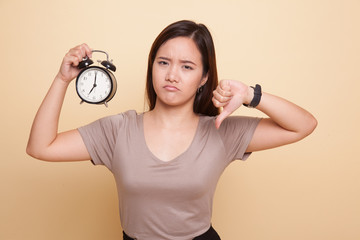 Young Asian woman thumbs down with a clock.