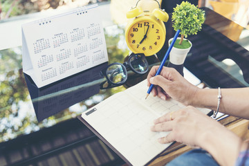 2022 Calendar planner agenda plan on  schedule event. Timetable agenda of wedding organizing timetable by organizer schedule. Woman hands writing agenda on calendar desk. Calendar event plan concept - obrazy, fototapety, plakaty