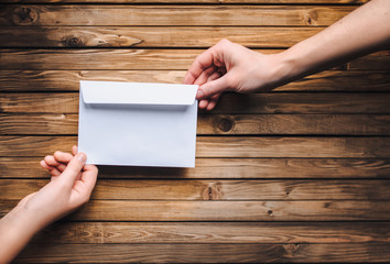 White envelope in the hands of two people. Online donation. The concept of writing. The Internet.