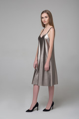 Young beautiful long-haired female model poses in silver grey dress