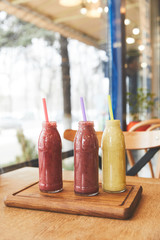 Bottles with assorted smoothies on wooden table