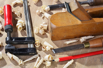 old  carpenter plane tools and wood shavings on wooden background.