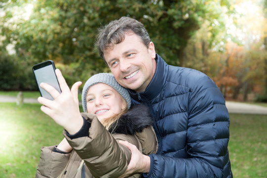 handsome father with cute blonde daughter make selfie in autumn winter outdoor smile and love
