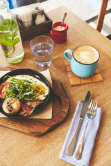 Morning meal with fried eggs served in pan and coffee