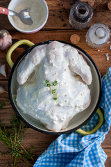 Raw whole chicken marinated in natural yoghurt with garlic and spices, top view, selective focus