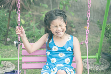 Asian girl sitting on the swing chair and feeling very happy