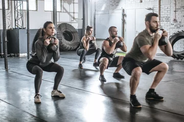 Gordijnen Sportmannen en sportvrouwen die gewichten heffen in de sportschool © LStockStudio