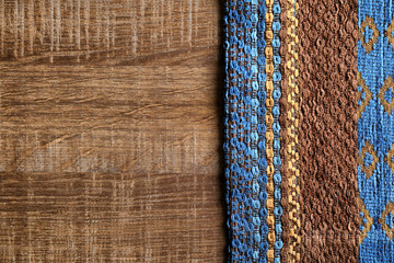 Patterned textile on wooden background. Fabric texture