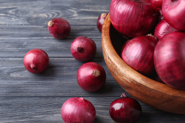 Bowl with red onion on wooden table
