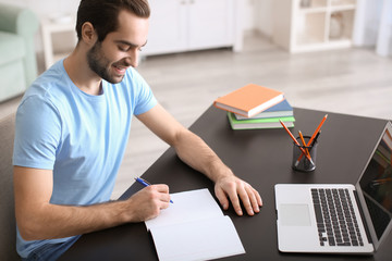 Student with laptop studying at table indoors
