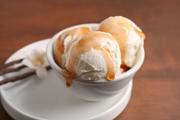 Bowl with delicious vanilla ice cream on table