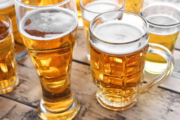 Glassware with fresh beer on wooden background